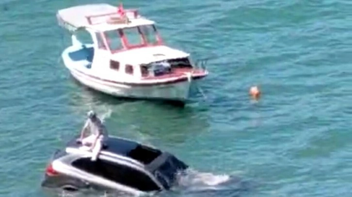 Balıkesir'de ilginç anlar: Denize uçan otomobilinin üzerinde oturup yardım bekledi